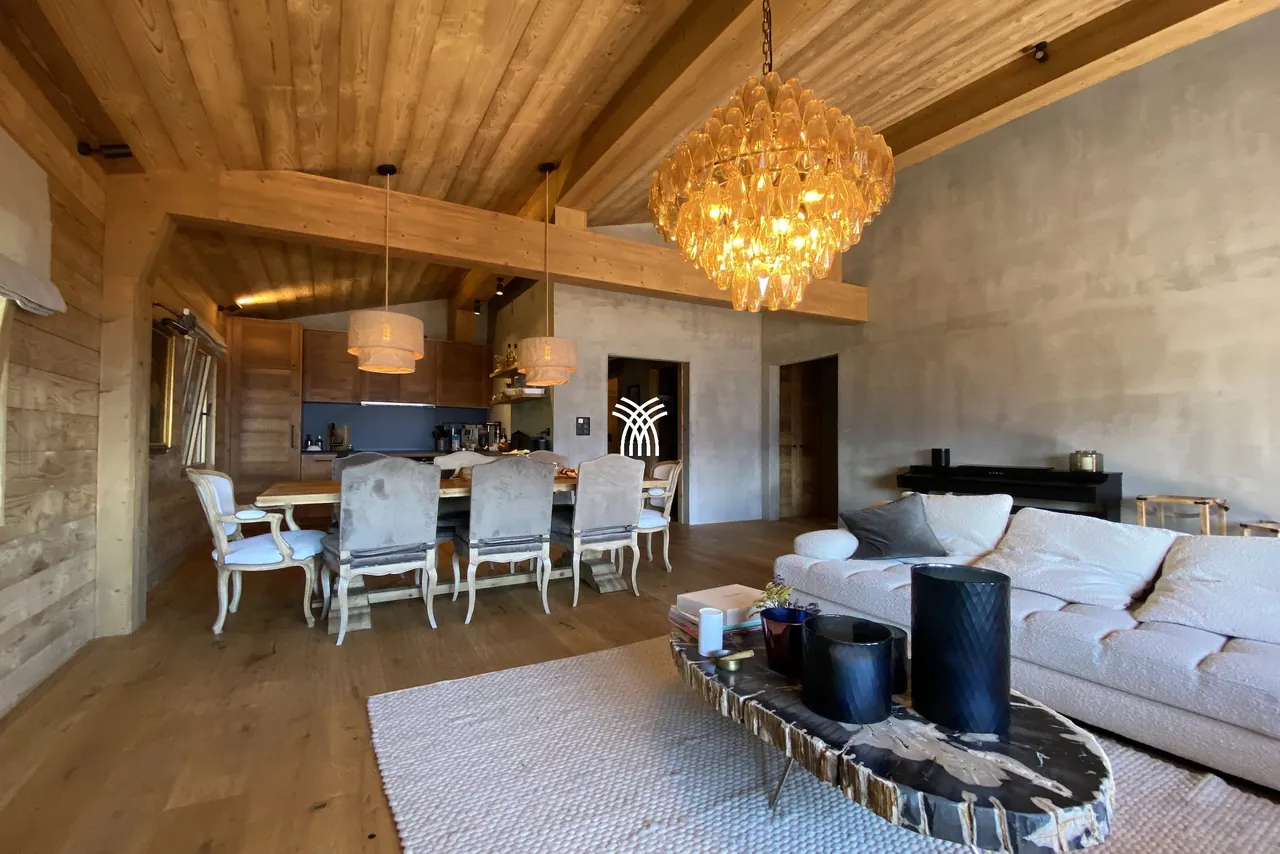 The living and dining room of Chalet Cervo, with a chandelier under the wood ceiling