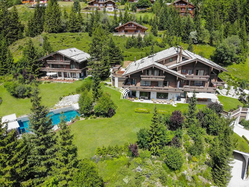 Aerial view of Chalet Christiana on green lawns in the pine forest, summer