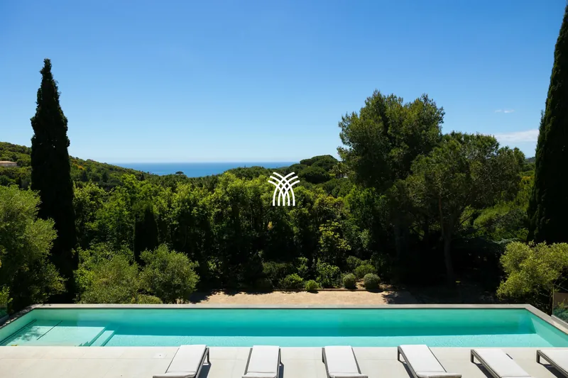 The long pool of Villa Texas between cypresses, with a glimpse of the sea